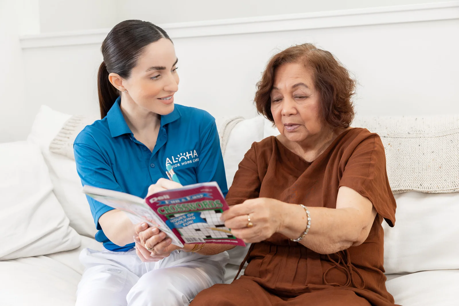 An Aloha caregiver and a senior working on a crossword puzzle together